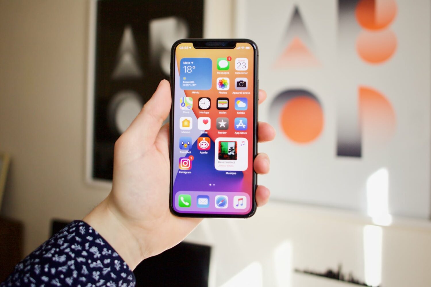 iPhone 14 Pro Max in a woman's hand, set against a wall with paintings